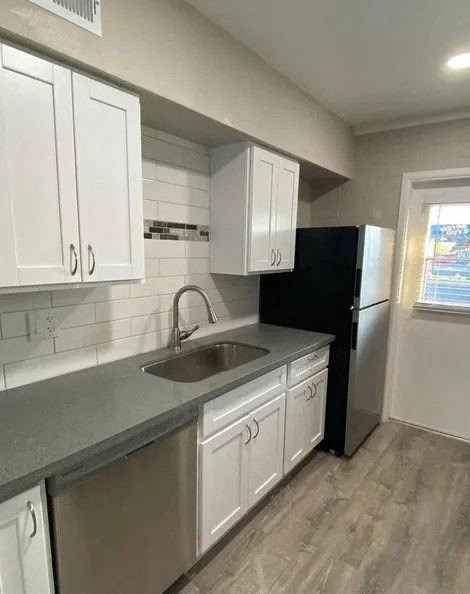 a kitchen with white cabinets and a sink and a refrigerator